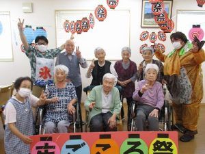 輪になってレクリエーションを楽しむ高齢女性と女性スタッフ