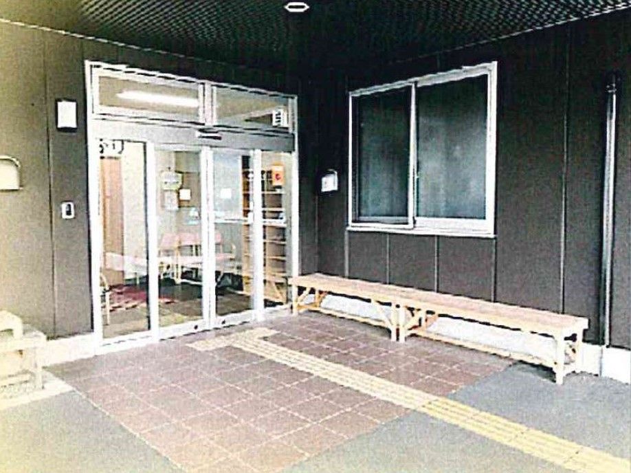 すっきりと無駄のないデザインの建物。シックな色合いの壁、エントランスに長いベンチがある