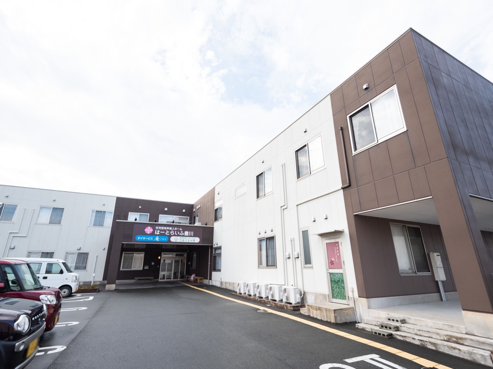 施設は屋根がフラットな長方形の建物である。外壁は白とこげ茶色の2色に塗り分けられている。建物の前に広がる敷地は、駐車場になっている。