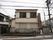 住宅街の中にある２階建てのグループホームである。２階部分の窓には、転落防止用のフェンスが取り付けられている。