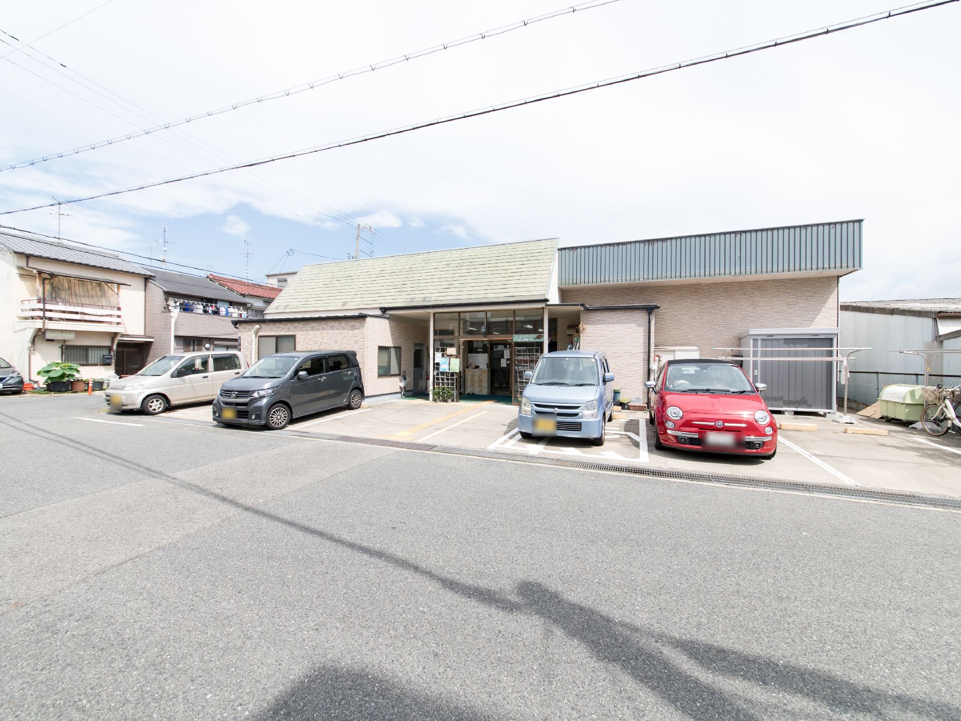 平屋建ての施設には、建物前に介護車両も止められる広さの駐車スペースを設けている。物干し台が設置されている。