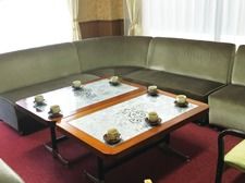 湯呑に入れられたお茶が置かれたテーブルを囲んで、エル字型のソファが設置されている。