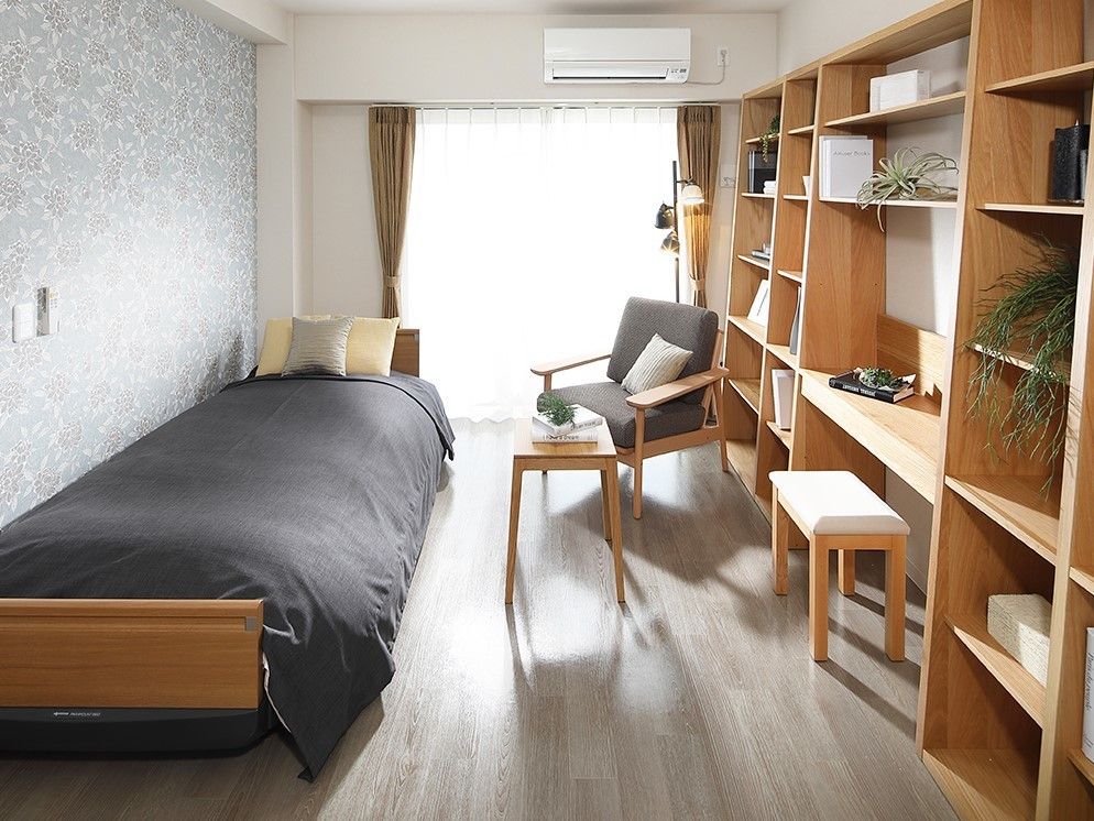 木製のベッドと大きな棚があり、薄いグレーの壁がおしゃれな居室