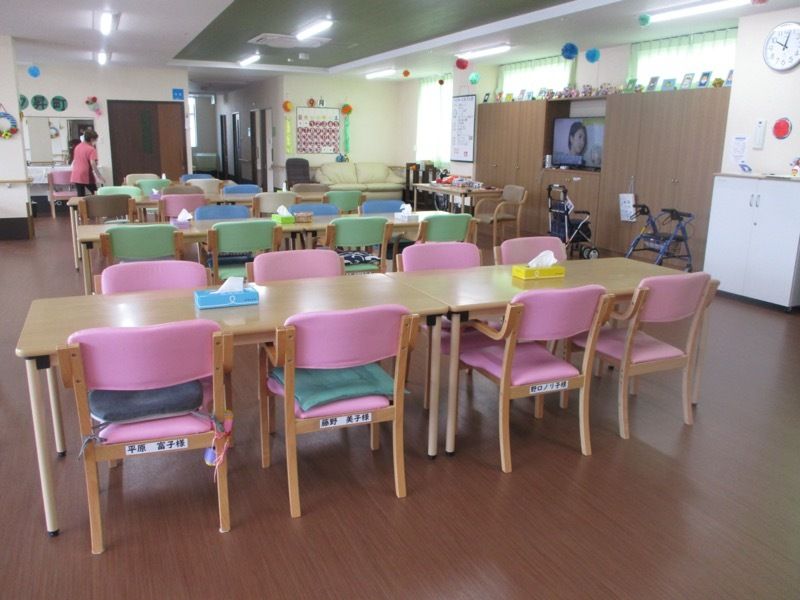 ピンクやライトブルーの椅子がセットされたダイニングテーブルセットが複数あり、歩行器などもある。