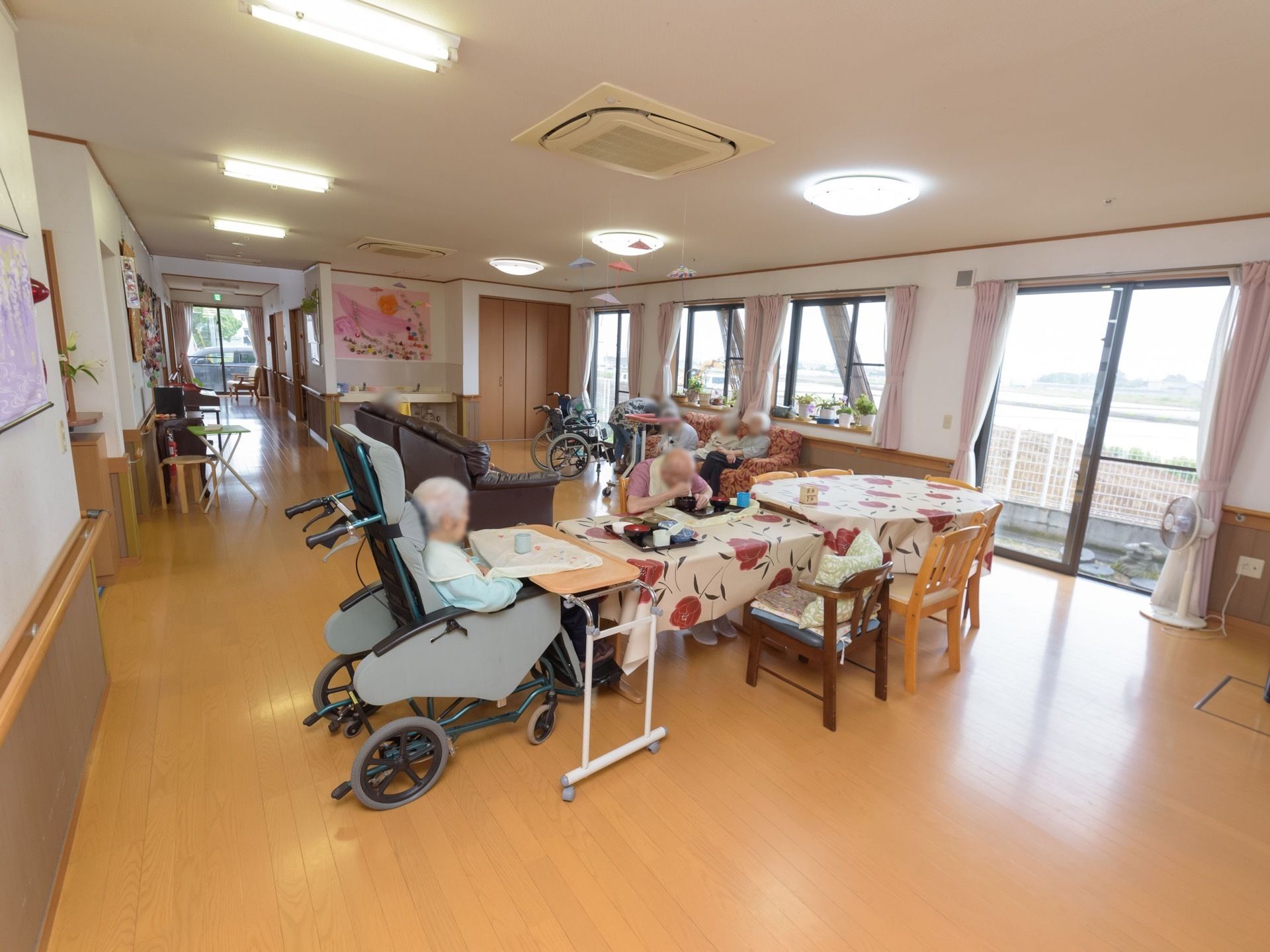 フローリングの床の部屋にテーブルやソファーなどがゆとりをもって配置されている。数ヵ所の窓から外の景色を眺めることができる。