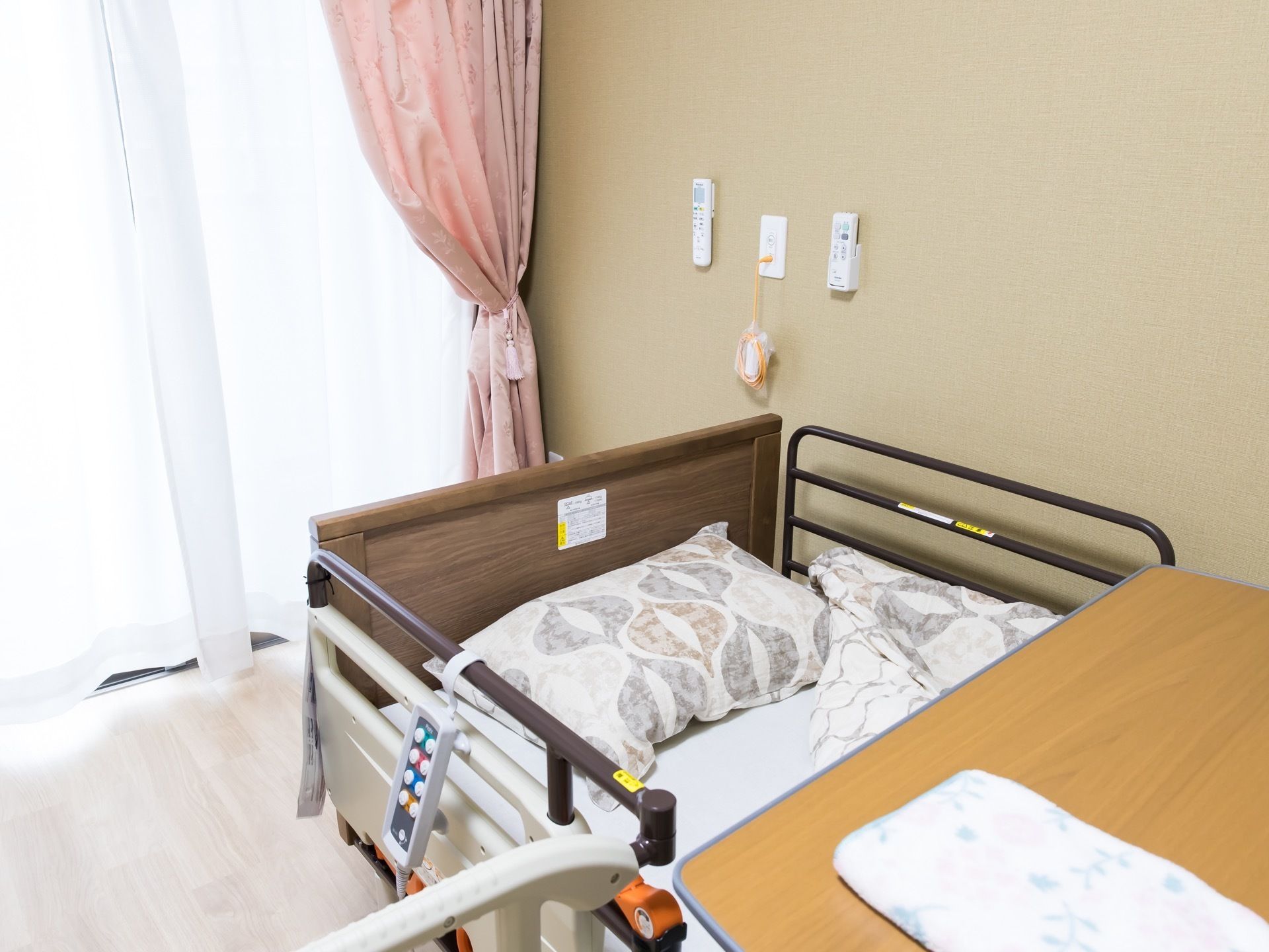 陽射しが差し込む居室の窓際にベッドが設置されている。転落を防止する柵があり、安心して眠ることができる。