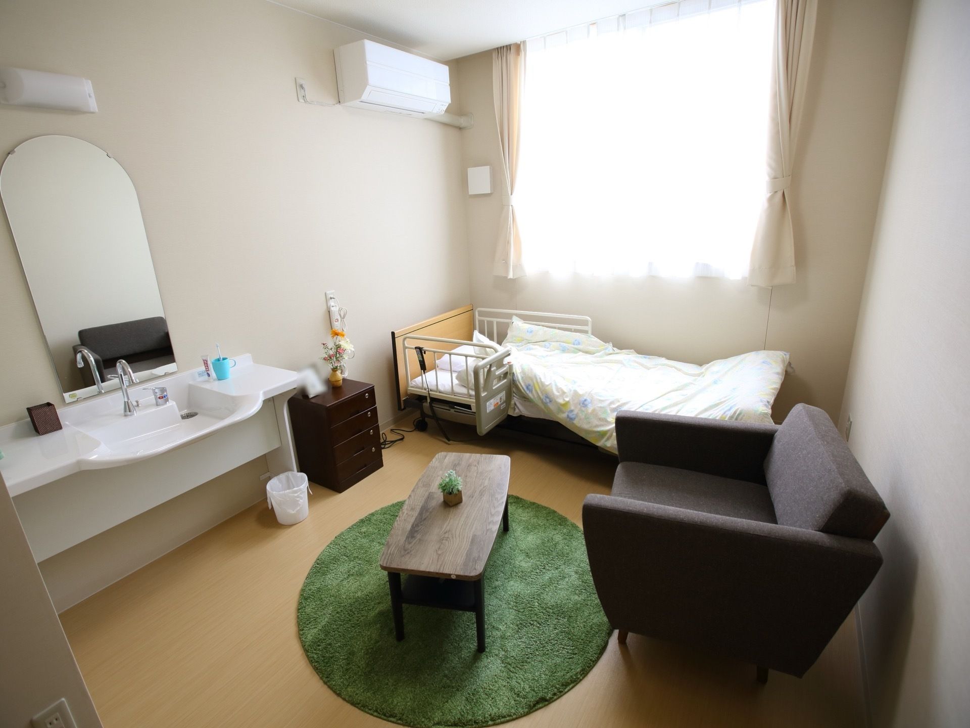 エアコンが完備されている居室で、窓からはたっぷりと外光が差し込む。ソファーやテーブル、ベッドなどの家具が置かれている。