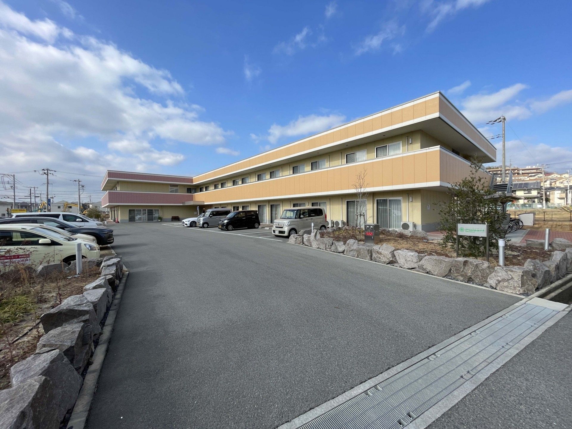 広い敷地内にはアスファルトが敷かれ、段差などがなくされている。2階建ての建物はブラウンを基調としている。