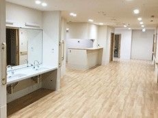 広い廊下に洗面台とキッチンスペース、リビングがある様子。施設内の共有スペースの写真