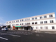 明るい日差しの施設外観と駐車場