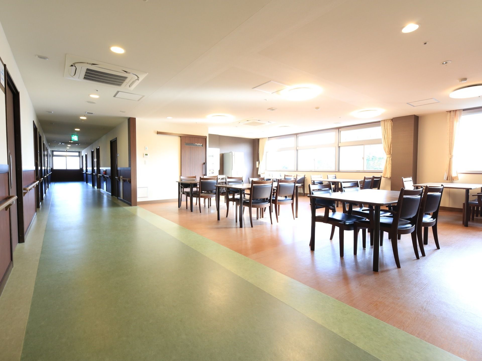 居室のドアが並んでいる、緑色の床の廊下のすぐ側に広い食堂がある。仕切りはなく、開放的な空間にテーブルと椅子が置かれている。