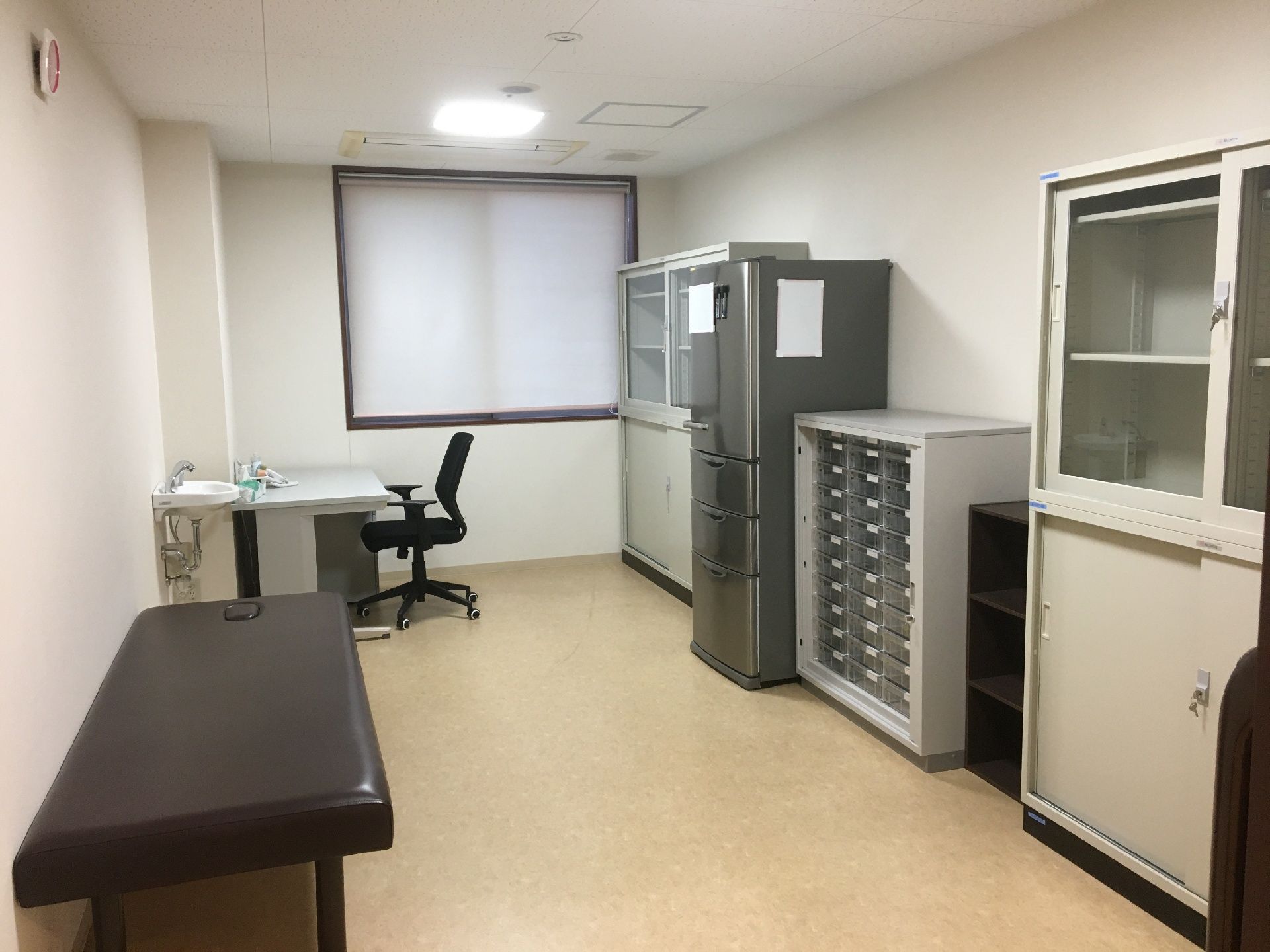 事務用机と診察台が置いてある診察室。病院のような設備がある部屋の様子