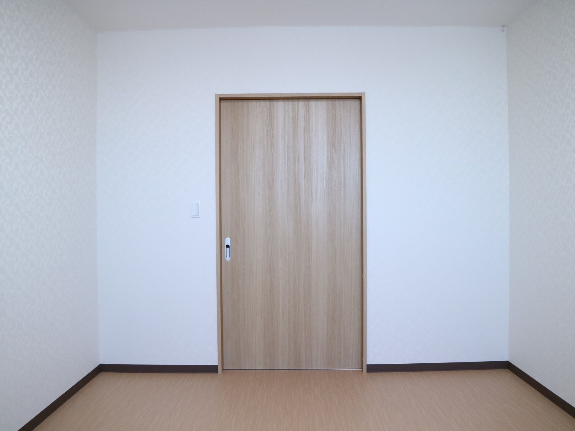 居室の入口はスライド式になっており、床は段差のないスムーズなフローリングになっている。壁には白色の壁紙が貼られている。