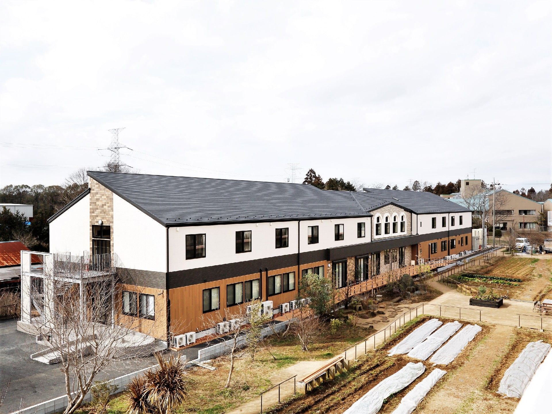2階建ての建物。1階部分はブラウン、2階部分は白で、広い駐車場もある。