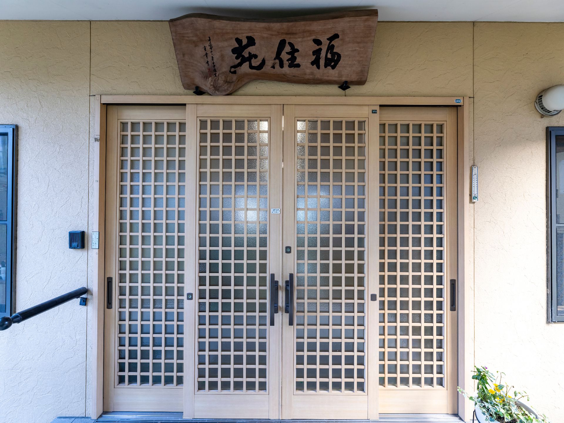 車いすの高齢者と手を握りながら話す介護スタッフの様子。施設内での会話の場面