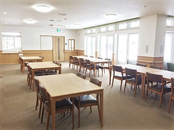 四人掛けのテーブルと椅子が置いてある広めのリビング。オールバリアフリーの床