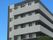 6階建ての建物はグレーと黒で、各フロアにベランダもある。