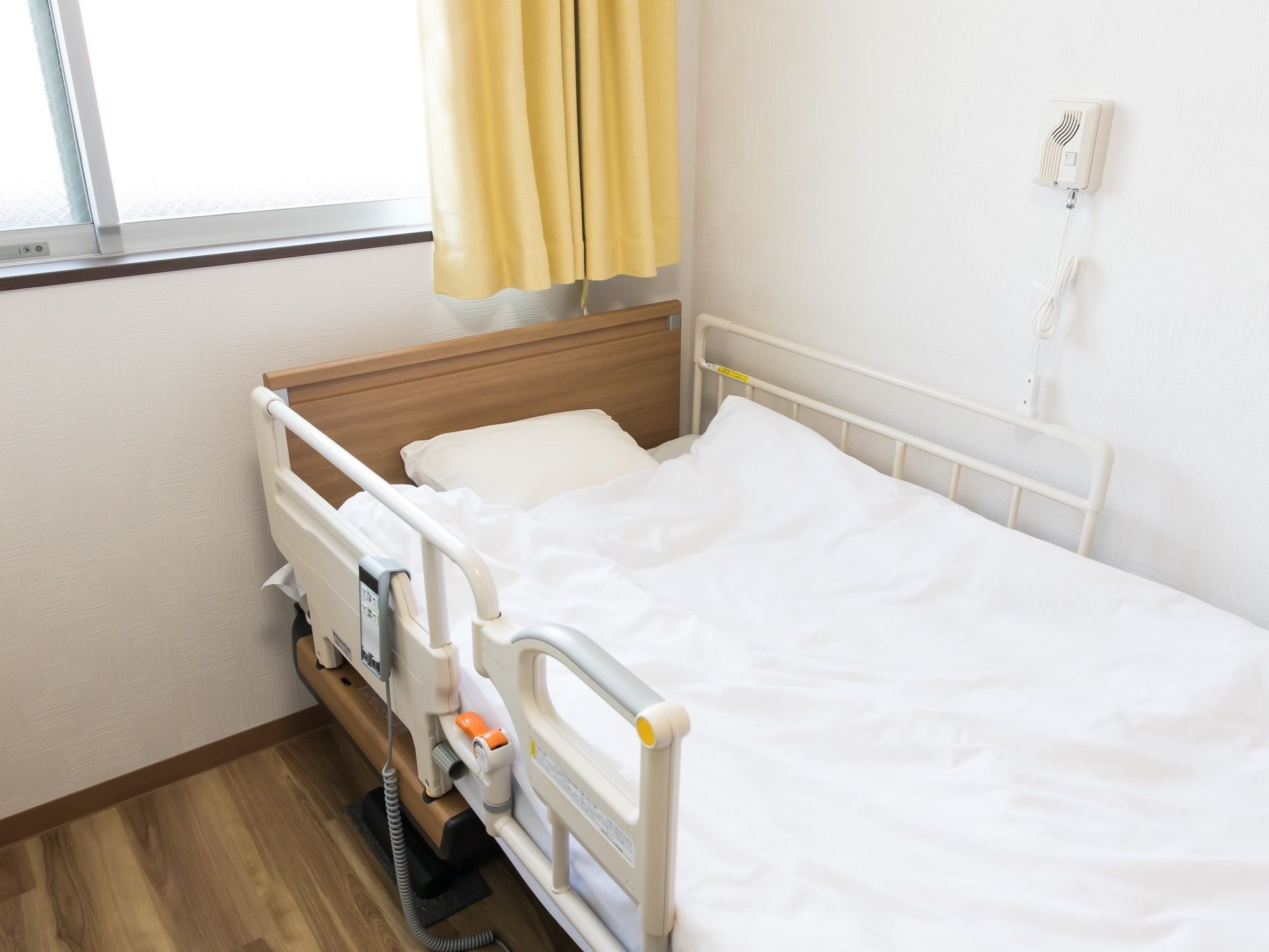 フローリング床の部屋である。壁際にベッドが置かれ、横壁に緊急通報装置が取り付けてある。高窓に、黄色のカーテンが掛かっている。