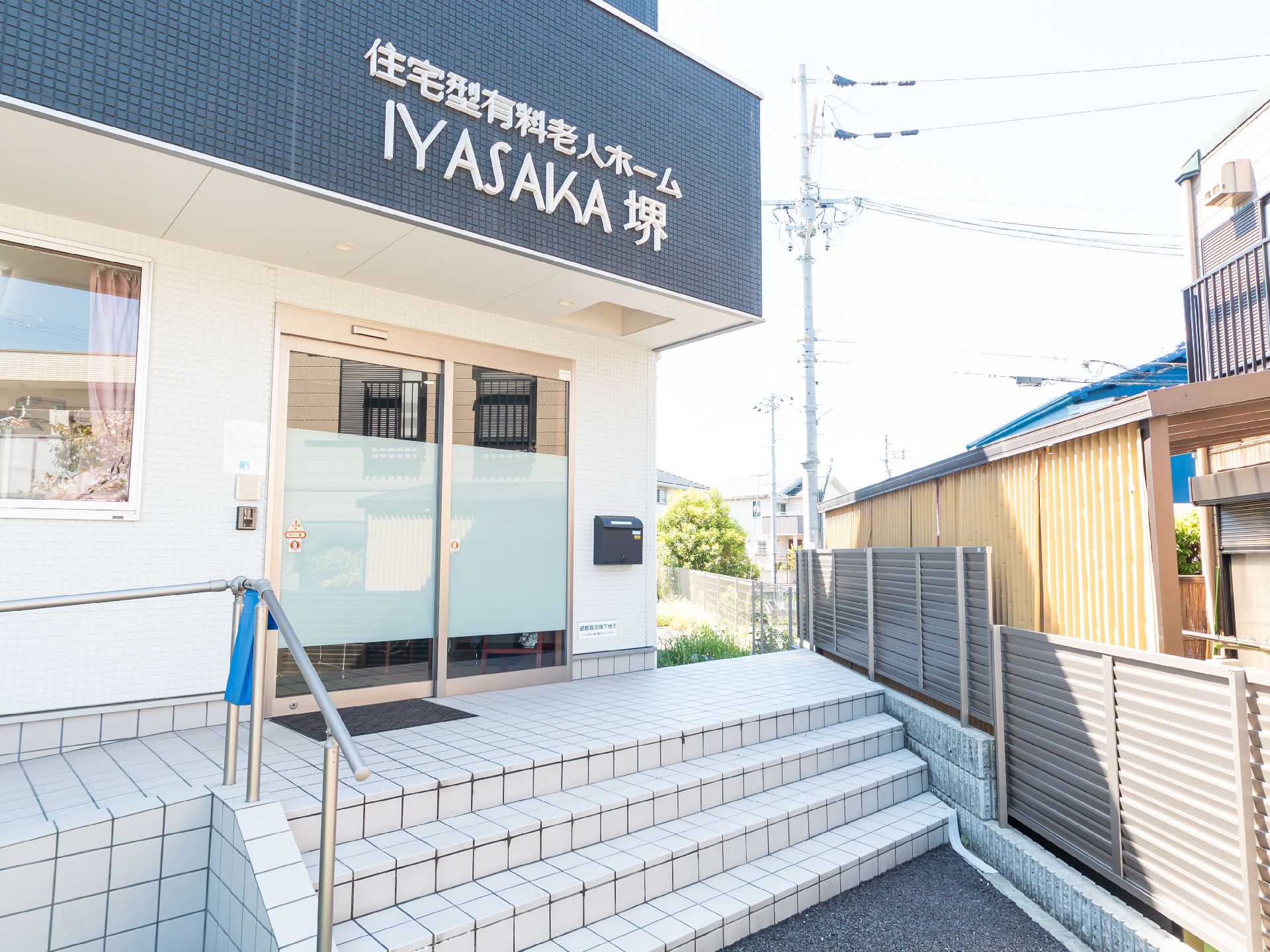 なにかを指さして笑顔で話している車いすの女性とそれを押している介護スタッフの様子