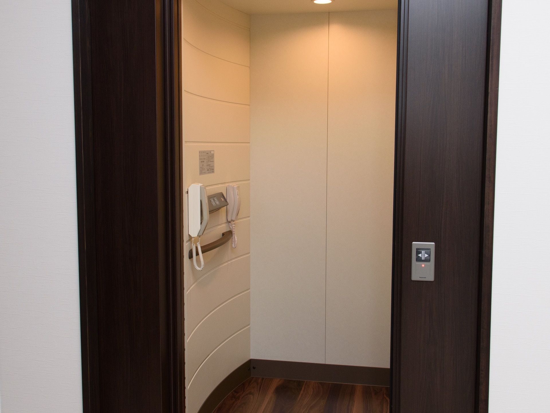 エレベーター内は白を基調とした明るい空間となっており、壁には電話や手すり、操作パネルが設置されている。
