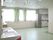 廊下から仕切り無く繋がった部屋に、キッチン設備や洗面台が置かれている。腰高窓には薄緑色のカーテンが掛けられている。