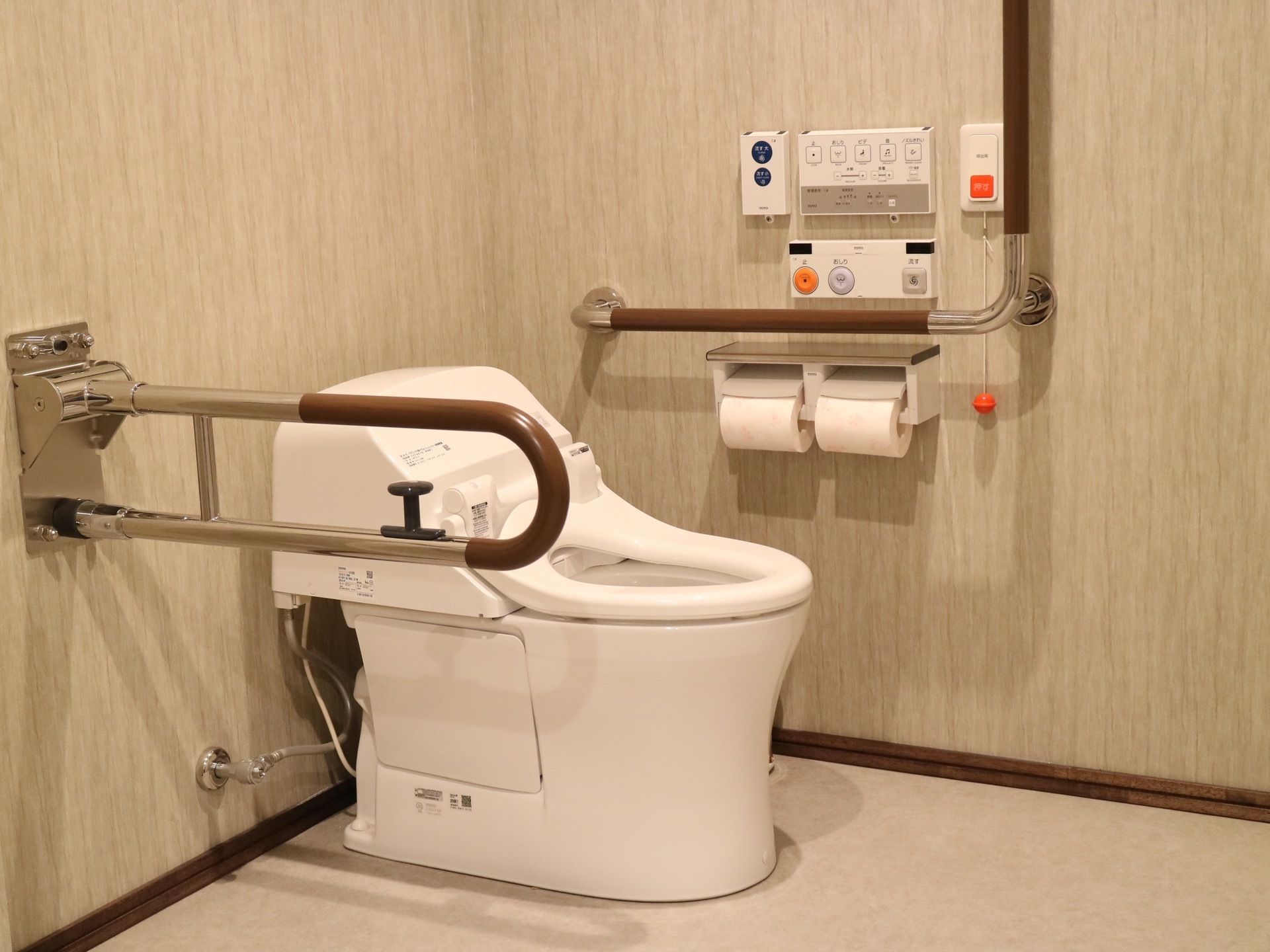 トイレには温水洗浄便座を設置している。手すりや非常ボタン、トイレットペーパーが壁に取り付けられている。