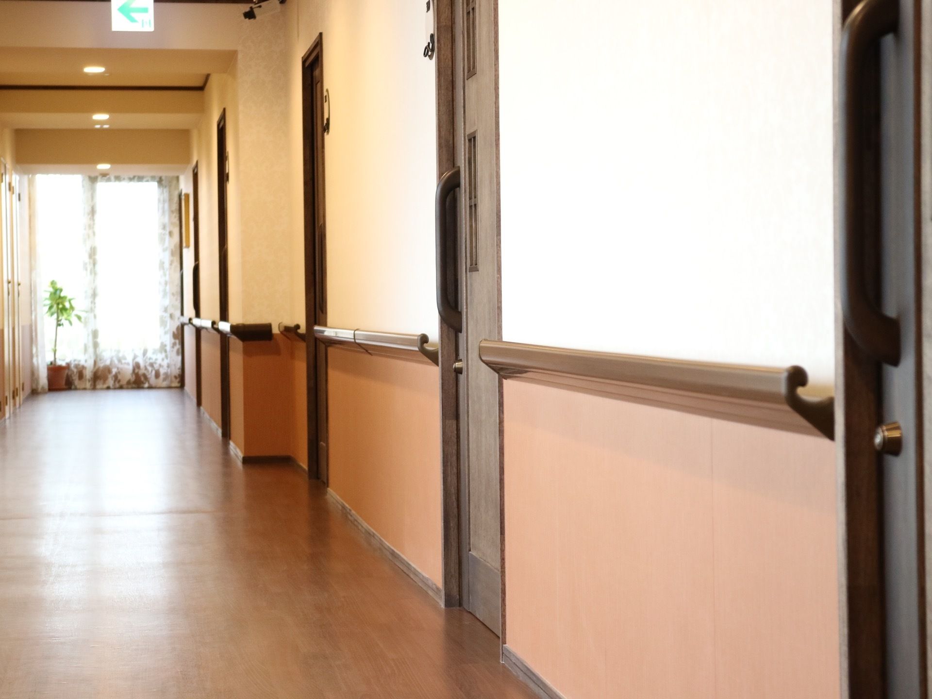 左奥へまっすぐ続く廊下で、突き当りは窓になっている。右手の壁には居室へ続くドアが等間隔に並んでいる。