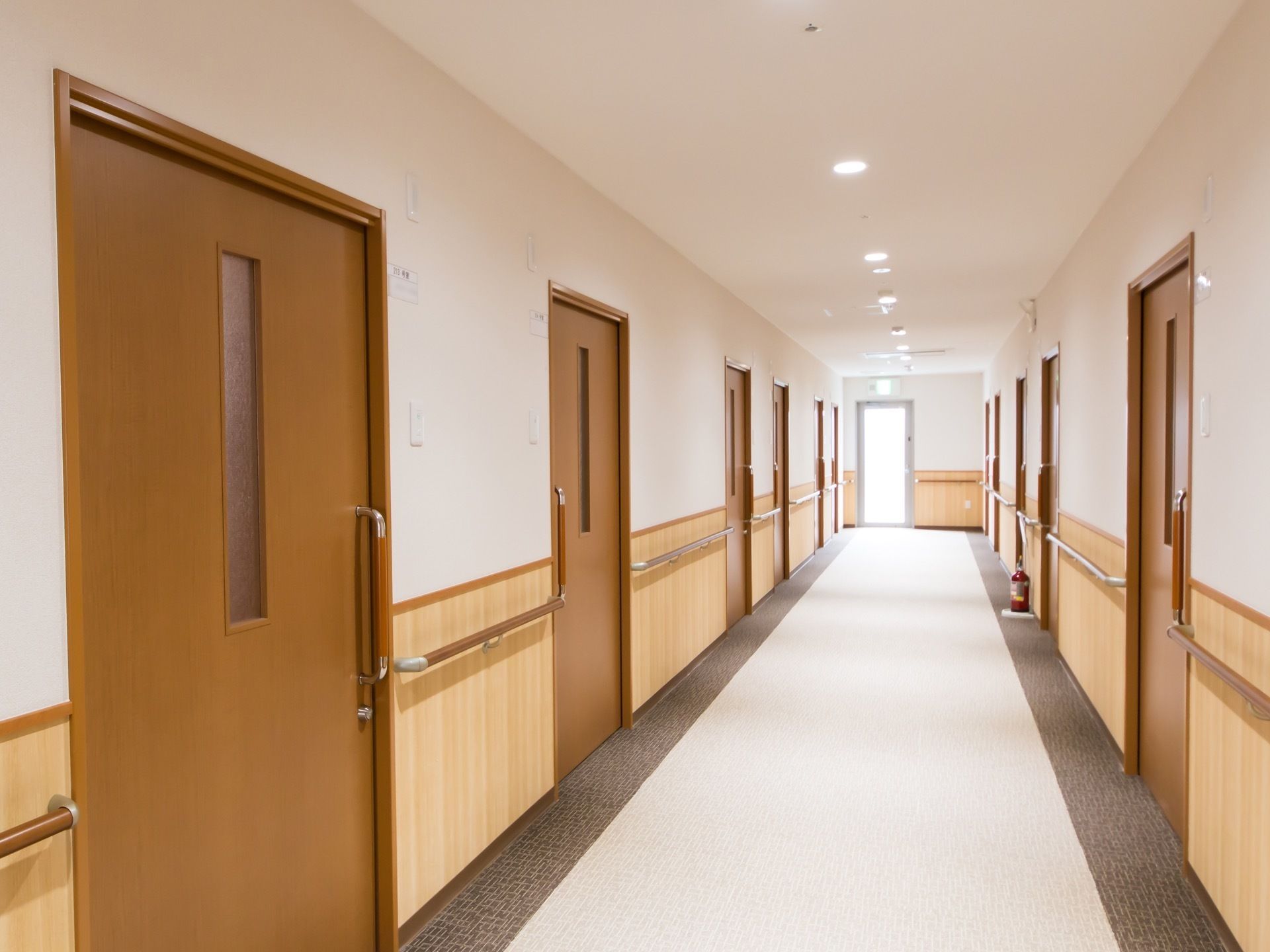 白色に、両縁がダークブラウンに色分けされた通路で、左右の壁に居室のドアと手すりが並んでいる。突き当たりに非常口がある。