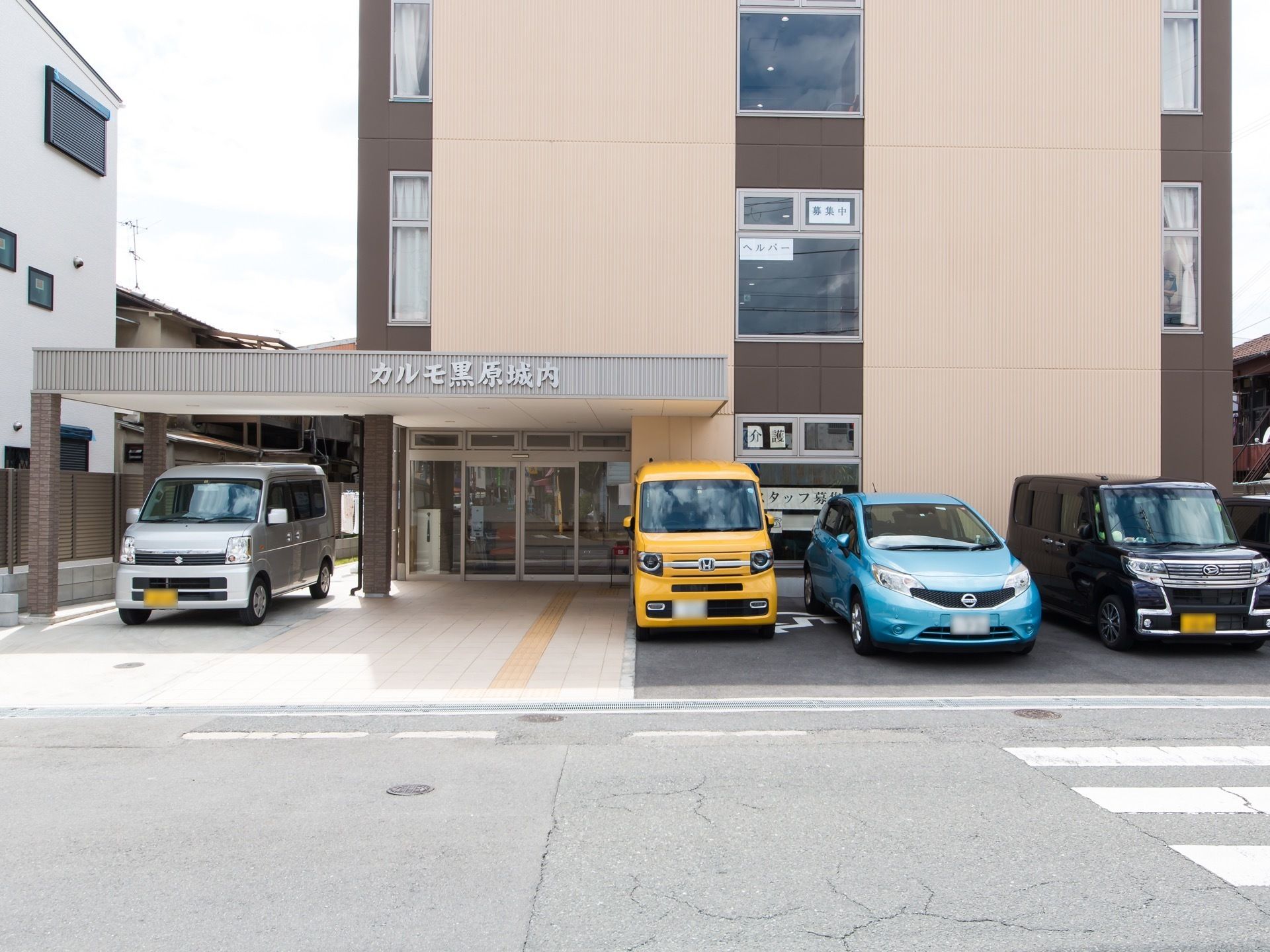 玄関前に車寄せがあり、建物の前に駐車スペースが設けられている。車寄せの屋根部分に、シルバーの文字で施設名が書かれている。