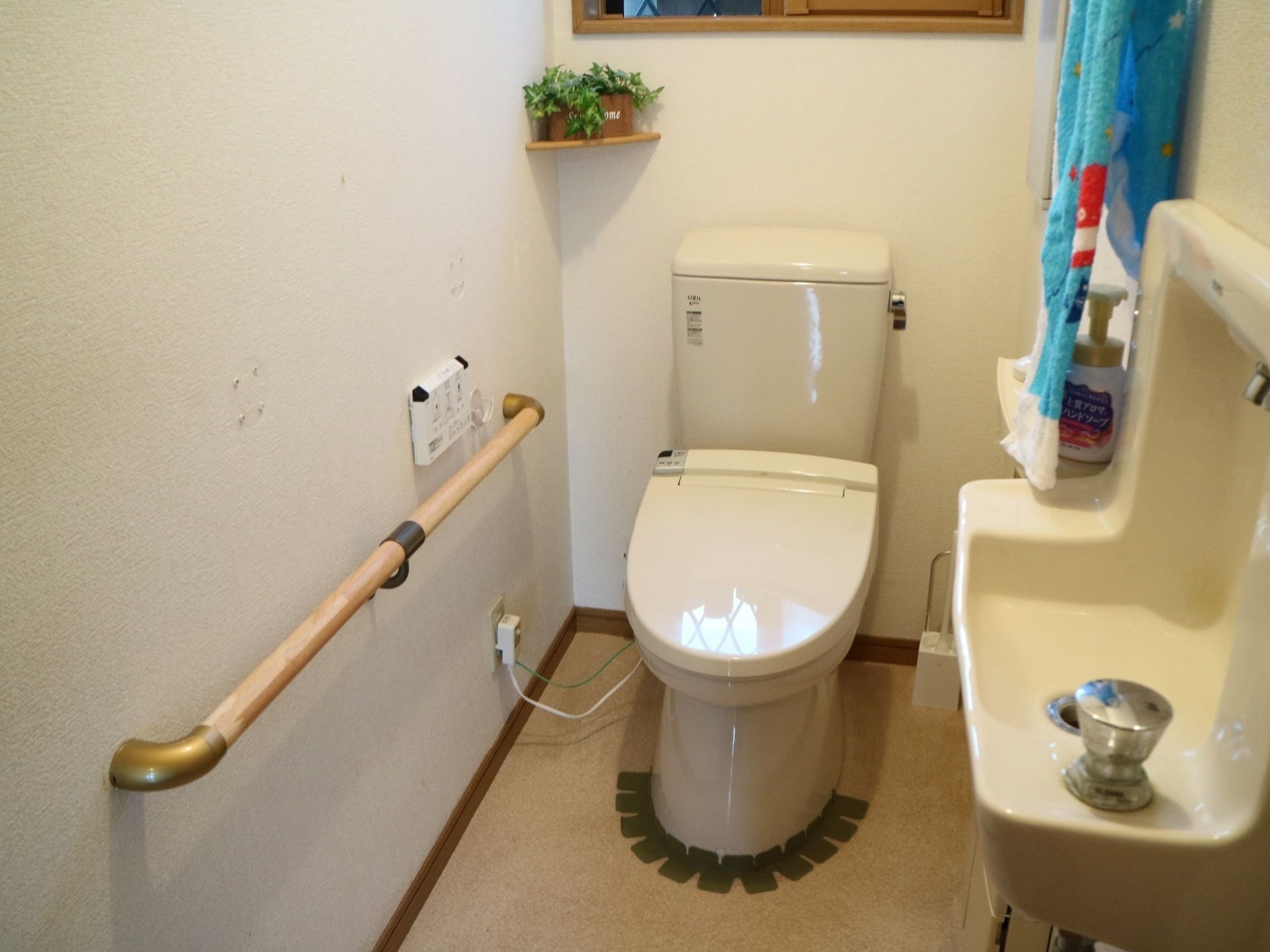 トイレには、温水洗浄便座器や手洗い場が完備されている。壁には手すりが設置され、飾り付けがされている。