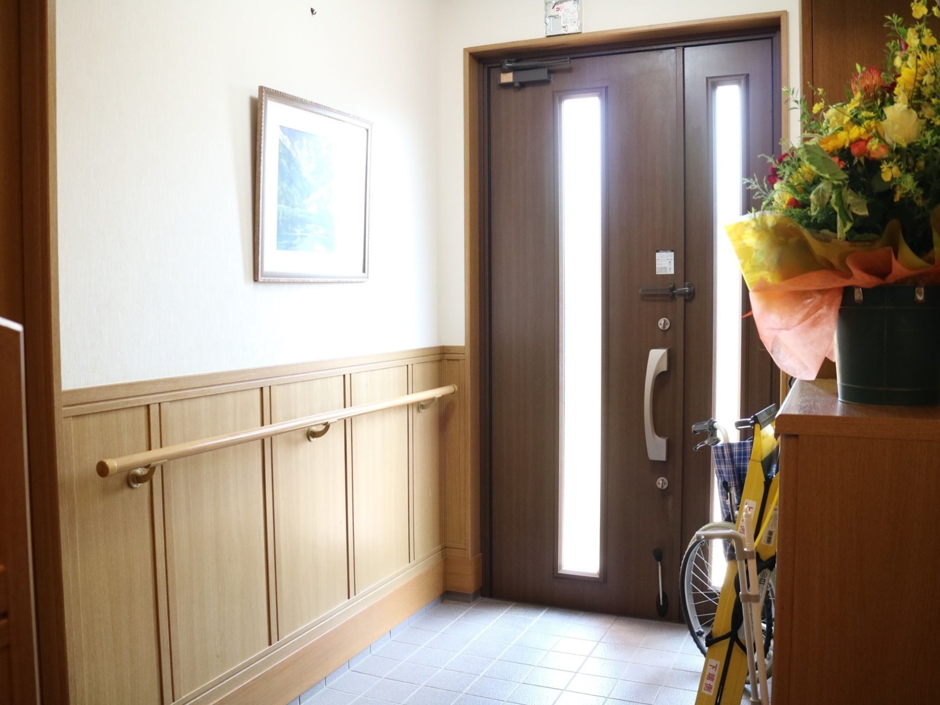 花が飾られ壁に手すりが設置された玄関