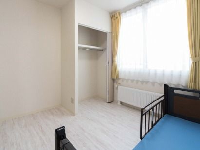 一人用のベッドと収納がついている小さな部屋の様子。窓際にカーテンがかかっている