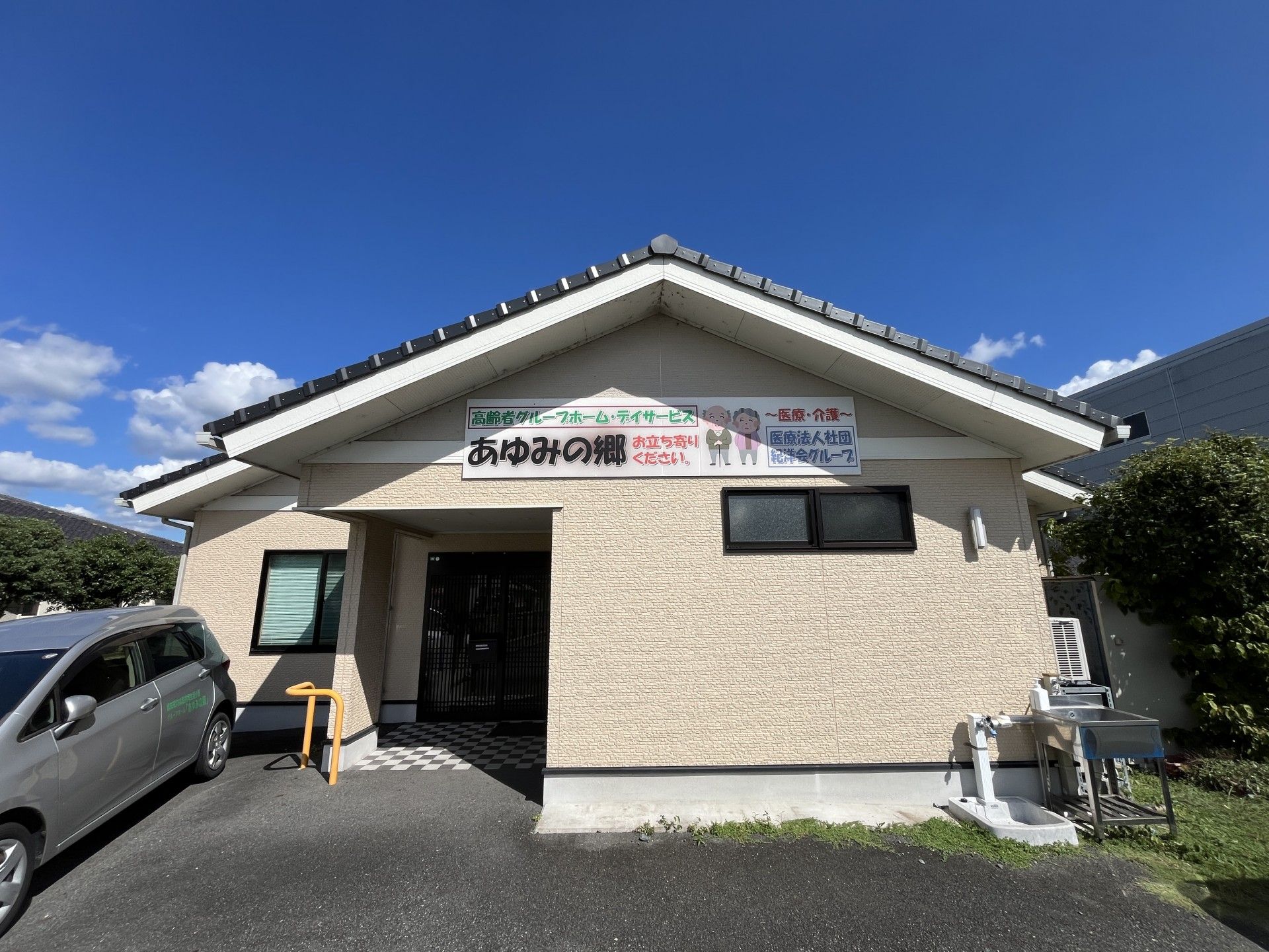 なにかに笑顔で手を振っている女性とその人の方を持ち同じ方向に笑顔を見せているスタッフ