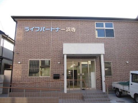 手すり付きのスロープが完備され外壁上部に施設名称のプレートが設置された施設玄関