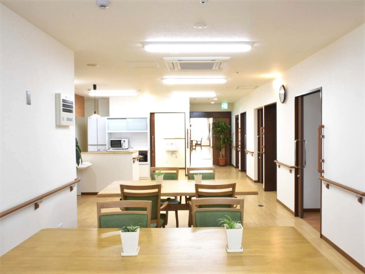 木製のダイニングテーブルが複数置かれ、ぬくもりが感じられる明るい食堂の奥にはキッチンもある。