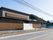 道路に面した場所に建っている、横長の建物がある。道路沿いの壁は木製の格子で覆われており、道路の境目には花壇がある。