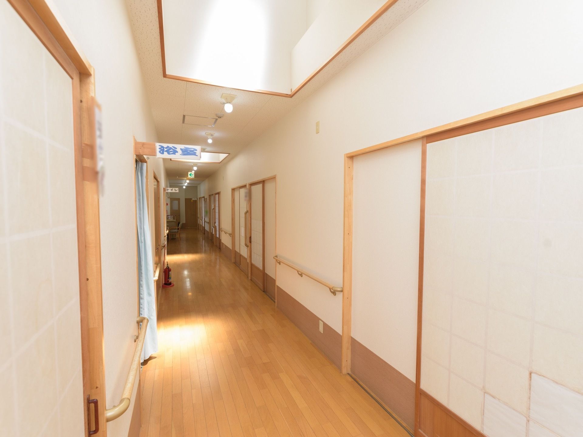 和洋折衷の内装が採用された通路。床は木目模様のフローリングで、壁には障子風の引き戸の扉が多数並んでいる。また、手すりも設置されている。