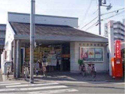 住宅のような三角屋根の小さな郵便局。入口周辺には何台もの自転車が停まっている。すぐ前に横断歩道がある。
