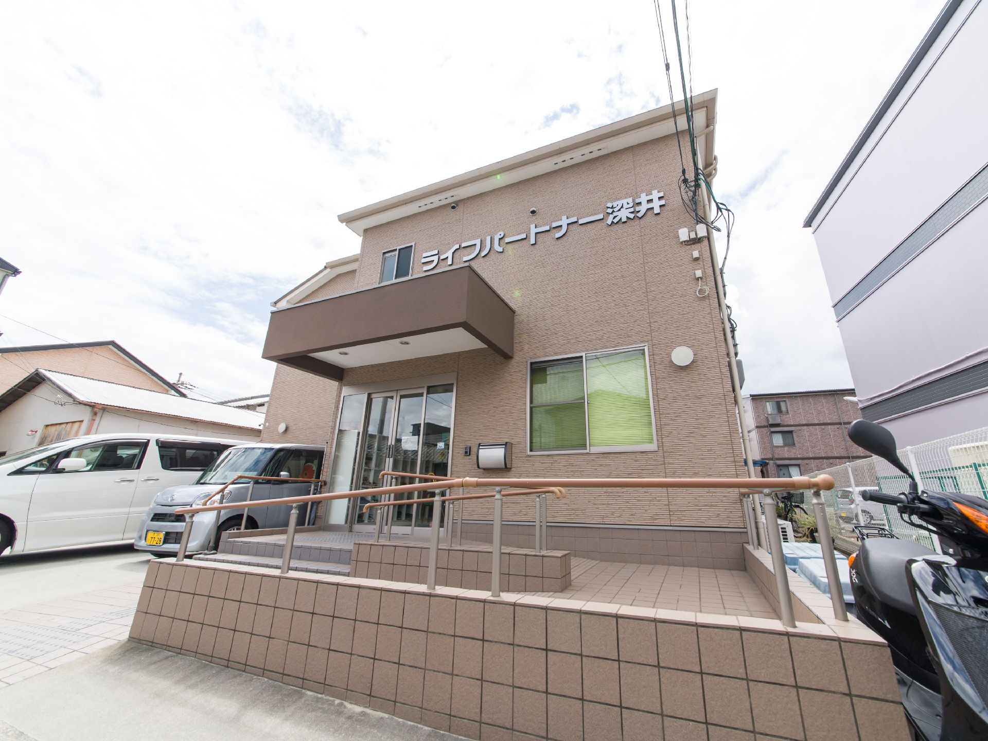 施設の出入り口は階段を数段上がったところにあり、扉の上部には庇がある。車椅子の方のために、スロープも設置されている。