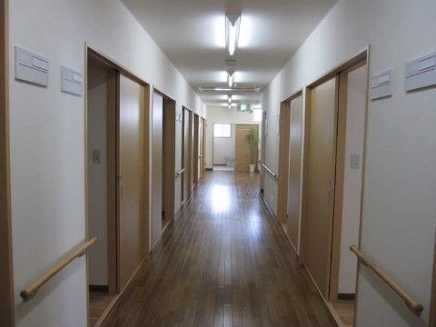 引き戸の並んでいる廊下。多くの引き戸が開けられ、内部が見えている。壁の上部には表札を入れるパネルがある。