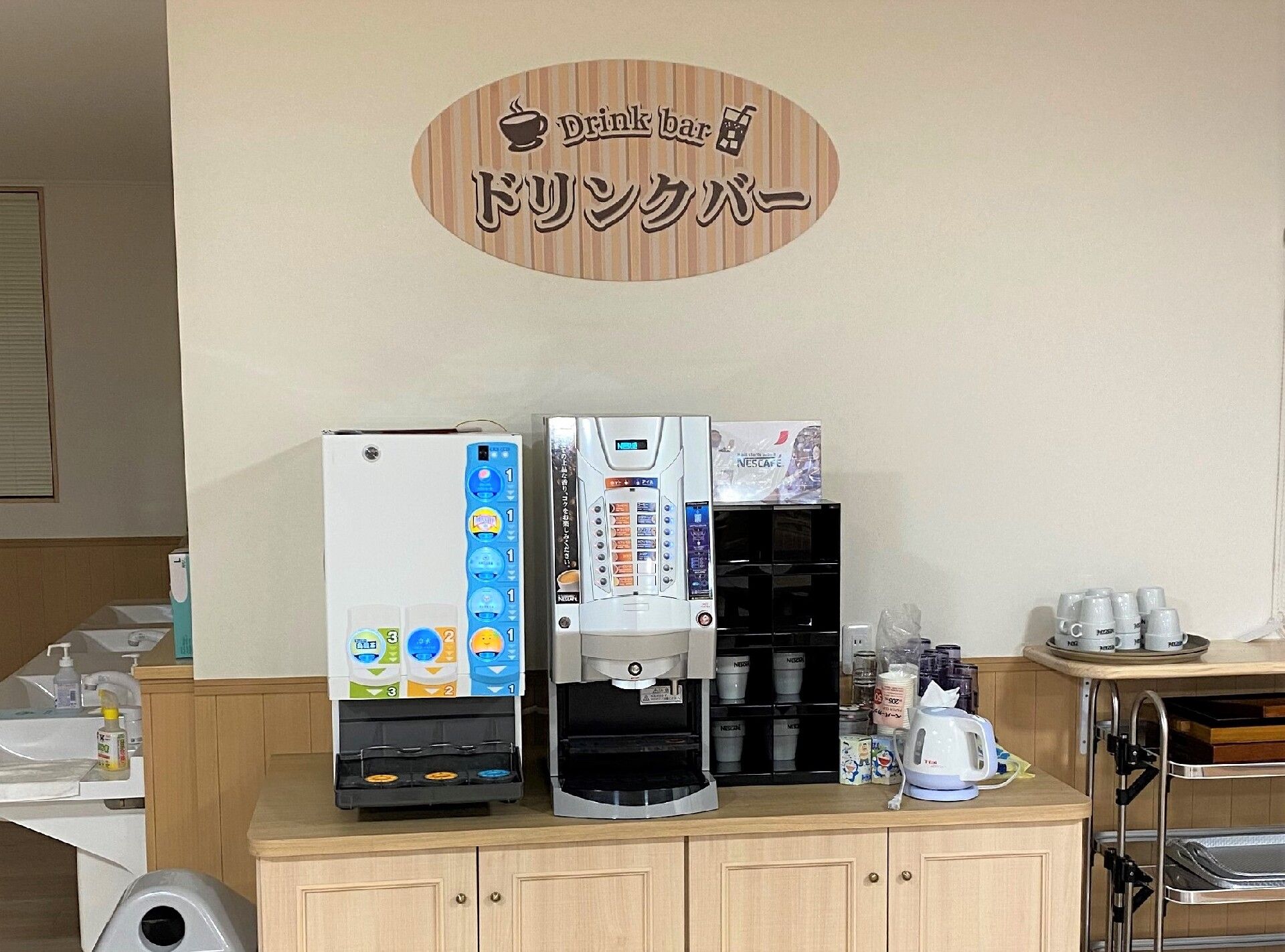 「ドリンクバー」と書かれたプレートの下には3種類のドリンクサーバーが設置され、好きなドリンクを飲むことができる。近くにはコップも置かれている。