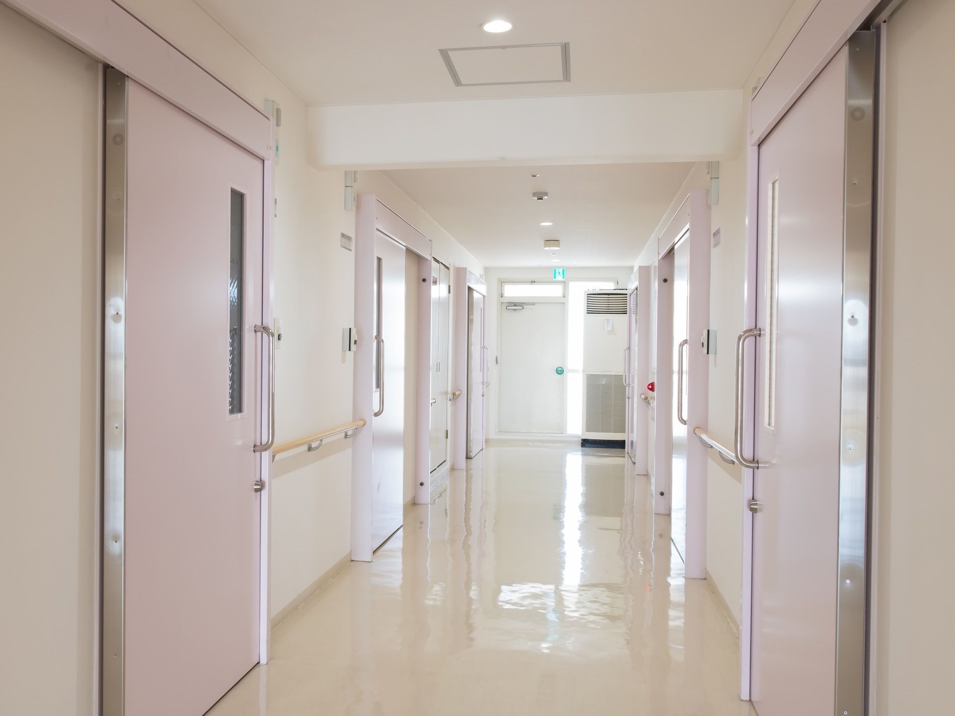 通路の突き当りに、非常口が設置されており、天井には非常口案内灯がある。また、壁には手すりが取り付けられており、居室入り口は薄いピンクである。