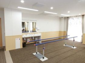 リハビリ用の平行棒が置かれたスペースには車いす対応の洗面所がある。