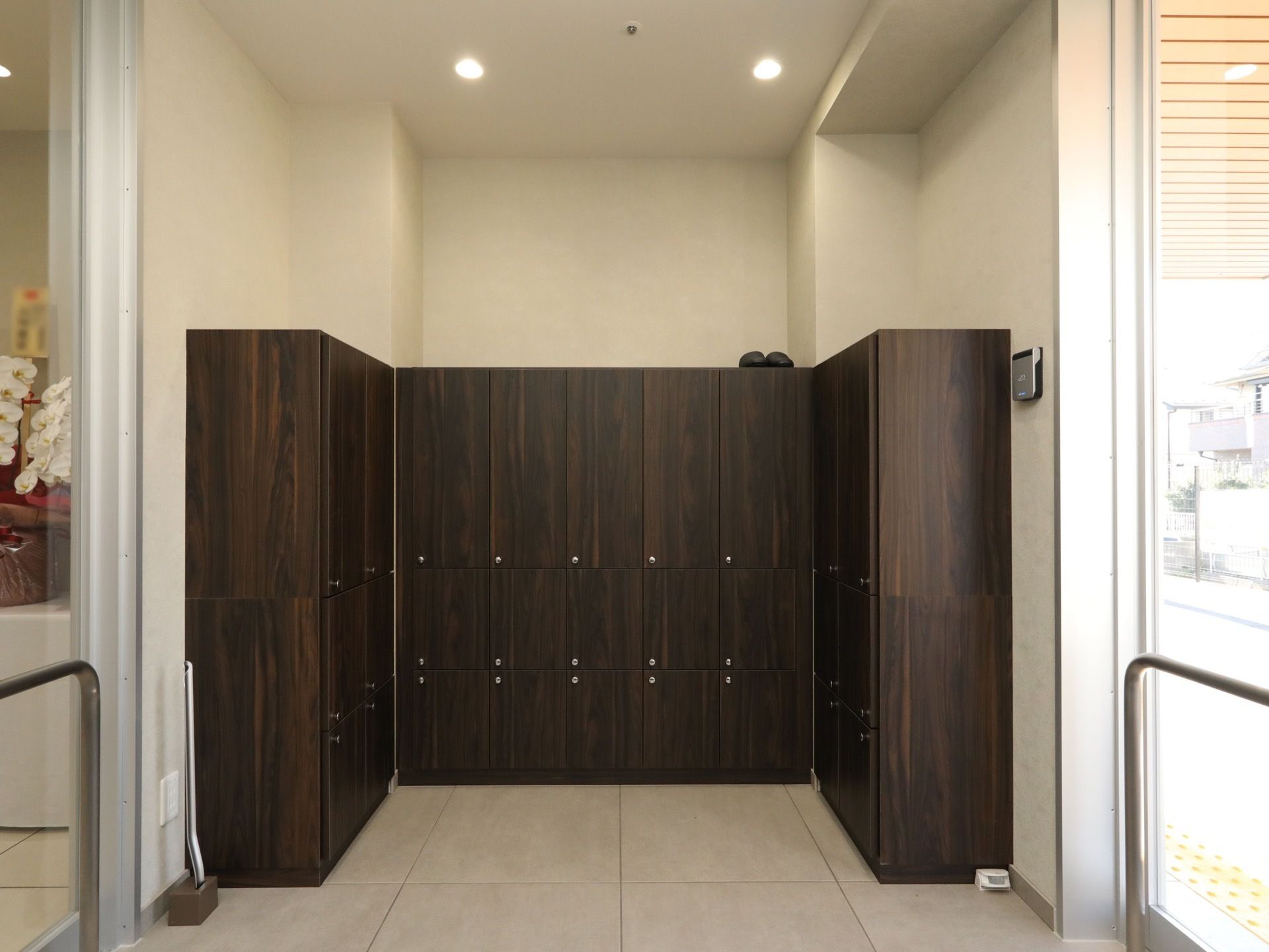 自動ドアと自動ドアの間の空間に、黒い扉の棚が設置してある。取っ手部分が銀色で、Ｕの字に並べられている。