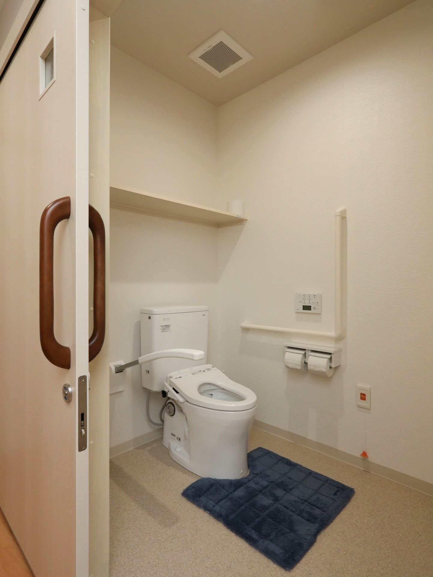 居室に備え付けられているトイレで、手すりやナースコールが完備されている。扉はスライド式で、鍵が掛けられるようになっている。