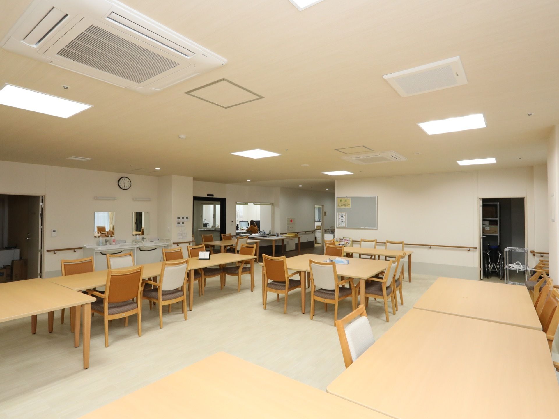 洗面台が設置されている食堂で、奥にスタッフルームが見える。天井には複数の照明が設置されており、明るい。