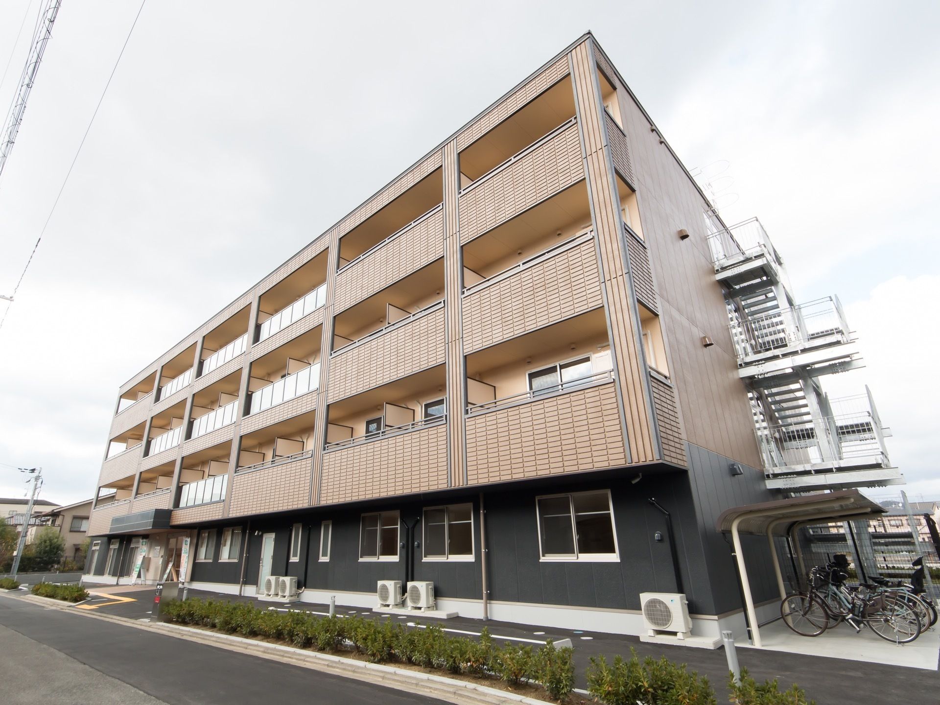 鉄骨造の４階建ての建物が建っている。建物の側面に非常用の階段が設置されていて、階段の隣には屋根付きの自転車置き場が設けられている。