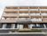 ４階建ての現代的なデザインの建物が正面にあり、その玄関の周囲には看板やのぼりが複数立てられているのが見える。