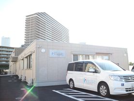 施設は明るいタイル張りの外観で、親しみやすい雰囲気の外観。敷地内には駐車スペースが複数設置されている。