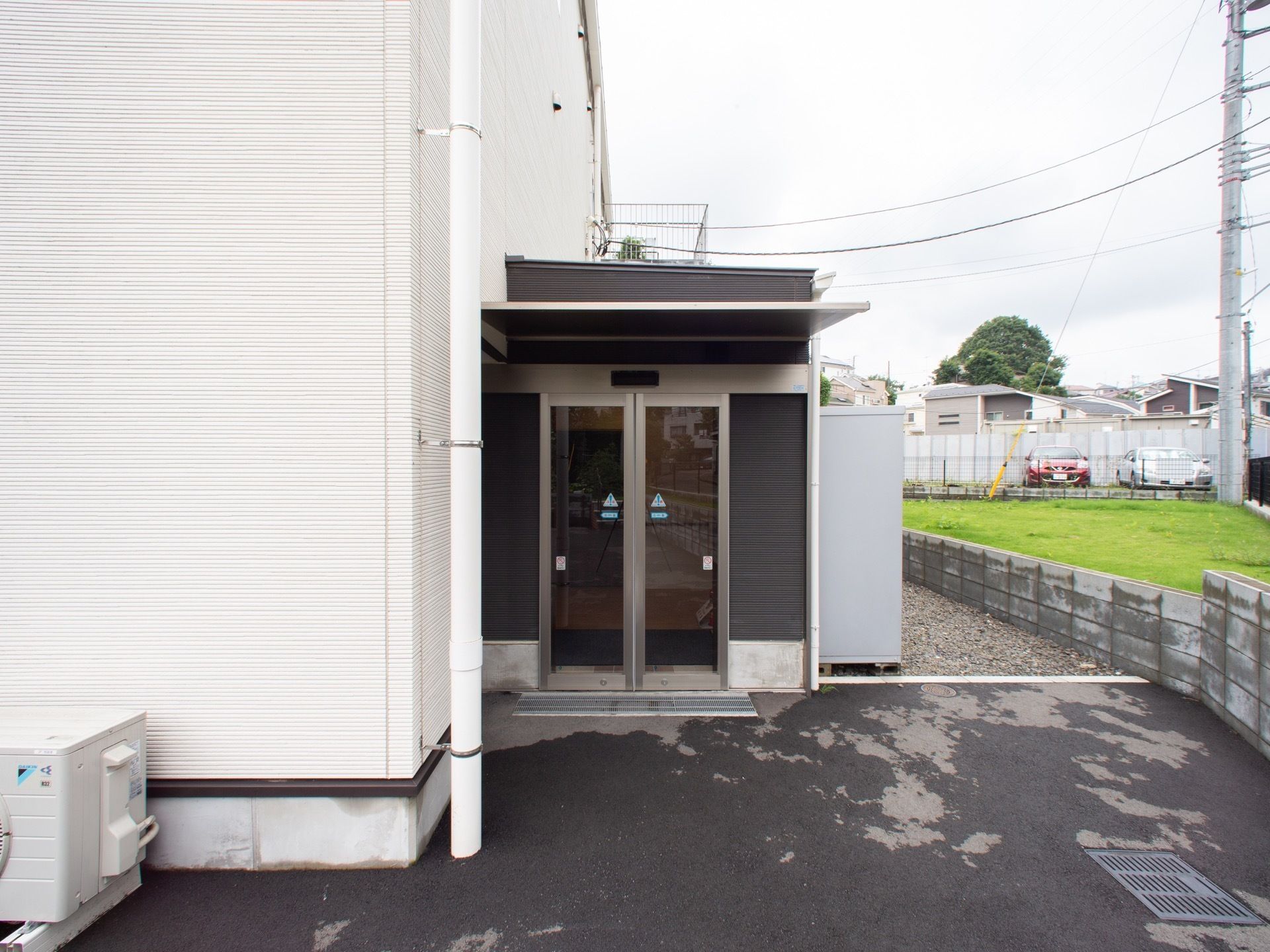 舗装された敷地にホームの建物があり、その脇に自動ドアの入口がある。周辺は戸建ての多い住宅地になっている。